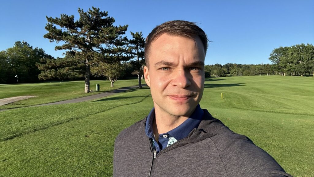 Kyle on a sunny golf course in a quarter-zip
